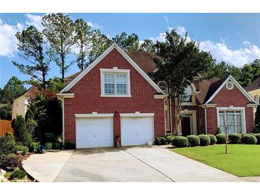 Charming two-story brick home featuring a well-manicured lawn and a two-car garage at 5018 Wickford Dr, Peachtree Corners, GA 30096