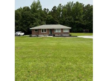 Charming brick home features a sprawling lawn and a backdrop of lush trees at 6900 Rockland Rd, Stonecrest, GA 30038