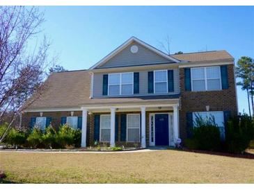 Charming two-story brick home featuring a manicured lawn, a welcoming front porch, and blue shutters at 8320 Mayfern Dr, Fairburn, GA 30213