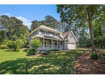 Charming two-story home featuring a welcoming front porch and lush, mature landscaping on a sunny day at 1655 Peachcrest Dr, Lawrenceville, GA 30043