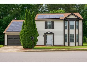 Inviting two-story home featuring solar panels, brown trim, a well-manicured lawn, and an attached garage at 3255 Hunters Crossing Pt, Lithonia, GA 30038