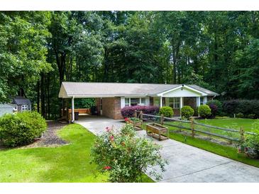 Charming single-story brick home with a covered carport, a well-manicured lawn, and a split rail fence at 514 Macedonia Forest Circle Cir, Canton, GA 30115