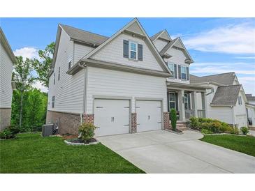 Side view of a two-story home featuring an attached two-car garage and well-maintained lawn at 4110 Morgan Elizabeth Way, Cumming, GA 30041