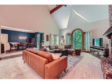 Spacious living room featuring a vaulted ceiling, fireplace, and large window with backyard views at 110 Boulder Dr, Roswell, GA 30075