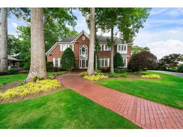 Beautiful brick home featuring manicured lawn, mature trees and a brick walkway at 2202 Lattimore Farm Nw Dr, Kennesaw, GA 30152
