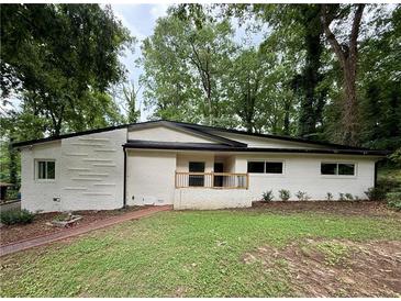 Charming single-story home with freshly painted white brick and a quaint front porch, nestled among mature trees at 2544 Overlook Dr, Atlanta, GA 30344