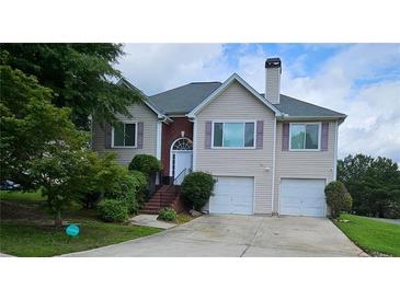 Inviting home featuring a two-car garage, well-maintained landscaping, and a classic brick chimney at 1338 Barrett Bluff Dr, Lawrenceville, GA 30045