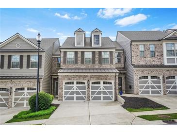 Charming brick townhome featuring a two-car garage and well-maintained landscaping at 228 Stone Park Dr, Woodstock, GA 30188
