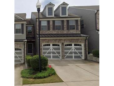 Charming two-story brick townhouse with a two-car garage and well-maintained landscaping at 228 Stone Park Dr, Woodstock, GA 30188