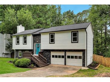 Charming two-story home with a beautifully landscaped front yard, a blue front door, and an attached two-car garage at 230 Sheringham Dr, Roswell, GA 30076