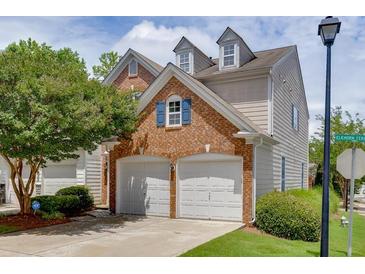 Two-car garage with brick facade and dormer windows, part of a charming townhome with a landscaped yard at 2421 Elkhorn Ter, Duluth, GA 30096