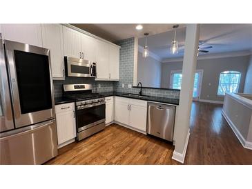 Modern kitchen featuring stainless steel appliances, white cabinetry, and hardwood floors at 793 Inman Mews Ne Dr, Atlanta, GA 30307