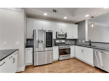 Modern kitchen featuring white cabinets, stainless steel appliances, granite countertops, and a light grey backsplash at 793 Inman Mews Ne Dr, Atlanta, GA 30307