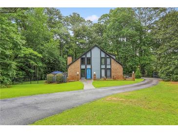 Charming exterior elevation of brick home features a blue front door and lush, green landscaping at 1605 Saint Tropez Way, Atlanta, GA 30350