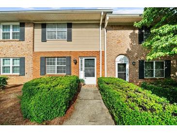 Inviting townhome featuring a brick facade, black shutters, and lush green landscaping at 406 Northdale Ct, Lawrenceville, GA 30046