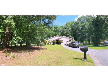 Ranch-style home boasts a well-manicured lawn, mature trees, and a circular driveway providing ample parking at 200 Fox Hall Court Ct, South Fulton, GA 30349