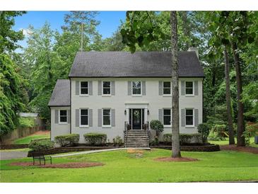 Charming two-story home with symmetrical windows, gray shutters, and a well-maintained front yard and garden at 7110 Northgreen Dr, Atlanta, GA 30328