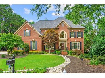 Charming two-story brick home featuring manicured lawn and mature landscaping at 130 Silver Mist Cir, Alpharetta, GA 30022