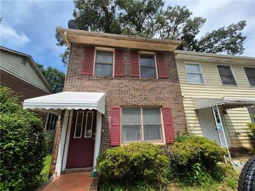 Charming two-story brick home with red shutters, a covered entryway, and a well-kept front yard at 964 Glynn Oaks Dr, Clarkston, GA 30021
