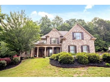 Charming brick home featuring a manicured lawn, dark wood shutters, and a welcoming front porch with stone columns at 208 Grandmar, Canton, GA 30115