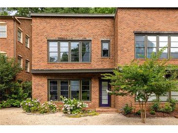 Brick townhouse featuring meticulous landscaping and a charming purple front door at 9071 Selborne Ln, Chattahoochee Hills, GA 30268