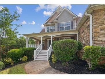 Charming two-story home featuring a covered front porch, landscaped yard, and stone and siding exterior at 167 Gothards Creek Dr, Powder Springs, GA 30127