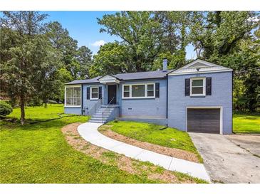 Charming home featuring a blue painted brick exterior, well-manicured lawn, and an attached one-car garage at 3211 Hollydale Drive Sw, Atlanta, GA 30311