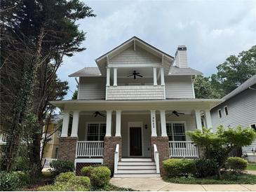 Charming two-story home featuring a welcoming front porch with brick and white pillars and landscaped yard at 2552 White Oak Dr, Decatur, GA 30032