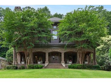 Elegant brick home featuring a covered front porch, manicured lawn, and mature trees at 1640 Nottingham Ne Way, Atlanta, GA 30309