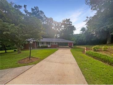 Charming single-story home with long driveway and mature trees on a sunny day at 2584 Favor Sw Rd, Marietta, GA 30060