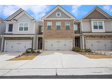 Charming townhome exterior featuring brick and gray siding, a two-car garage, and a well-maintained driveway at 5316 Radford Loop, Fairburn, GA 30213