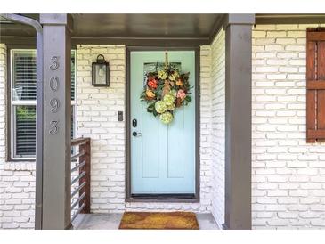Charming front door features a teal door with a floral wreath and a brick surround, enhancing curb appeal at 3093 Del Monico Dr, Decatur, GA 30032