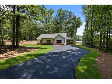 Charming single-story home with an extended driveway and a covered carport, surrounded by lush greenery at Lot 2 Harmony Rd, Temple, GA 30179