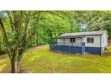 Charming home with blue skirting, covered porch, and lush greenery at 1841 Mobley St, Austell, GA 30106