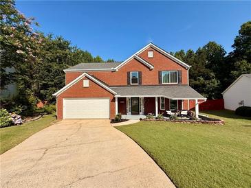Charming two-story red brick home with an attached garage and well-manicured lawn at 5388 Silver Springs Dr, Sugar Hill, GA 30518