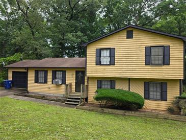 Charming yellow home with dark shutters, a well-manicured lawn, and mature trees in a serene, verdant setting at 234 Park Place Dr, Lawrenceville, GA 30046