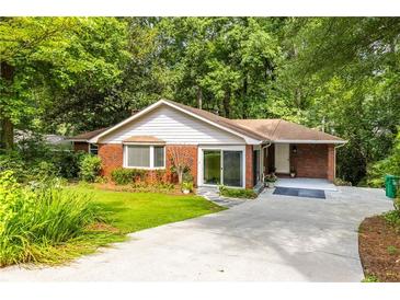 Charming brick home featuring a well-manicured lawn, mature trees, and a concrete driveway at 1102 Rogeretta Ne Dr, Atlanta, GA 30329