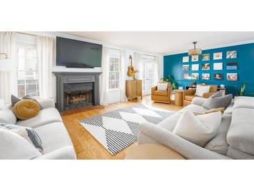 Bright living room featuring a fireplace, large TV, hardwood floors, and comfortable sofas at 1348 Sheffield Glen Ne Way # 8, Atlanta, GA 30329