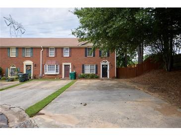 Brick townhome featuring a private driveway, manicured lawn, and a traditional-style entrance at 5567 Executive Way, Norcross, GA 30071