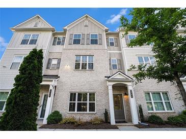 Beautiful townhome featuring a brick facade, gray shutters, and a well-maintained front yard at 1704 Evenstad Way, Smyrna, GA 30080