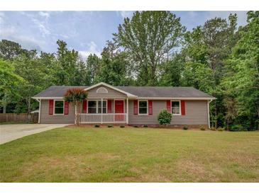 Charming single-story home featuring a landscaped lawn and a welcoming front porch with red door and shutters at 170 Hidden Pines Dr, Covington, GA 30016