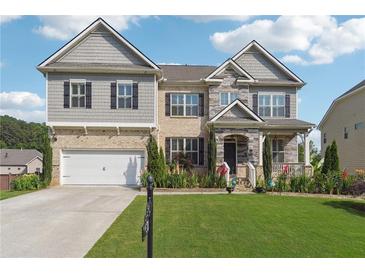 Charming two-story home featuring brick, stone accents, a manicured lawn, and an attached two-car garage at 1730 Dahlia Dr, Cumming, GA 30040