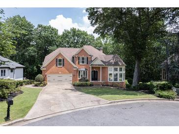 Charming two-story brick home with a well-manicured lawn and attached two-car garage at 6185 Masters Club Dr, Suwanee, GA 30024