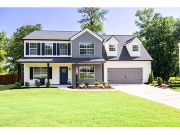 Charming two-story home featuring a well-manicured lawn, a two-car garage, and a welcoming front porch at 2720 Meridian Ct, Dacula, GA 30019