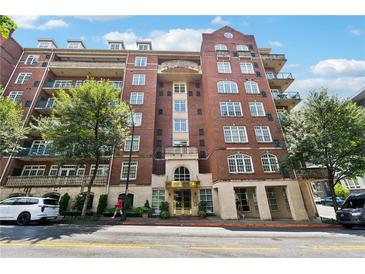Brick condo building featuring multiple stories, balconies, manicured landscaping, and a covered entry at 77 Peachtree Ne Pl # 101, Atlanta, GA 30309
