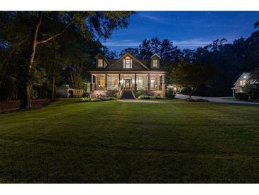 Inviting two-story home with a sprawling lawn, covered porch, and manicured landscaping at twilight at 654 Cannon Rd, Sharpsburg, GA 30277