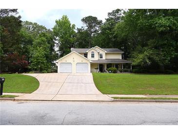 Inviting two-story home featuring a welcoming front porch and an attached two-car garage with a spacious driveway at 9130 Charlton Pl, Douglasville, GA 30135