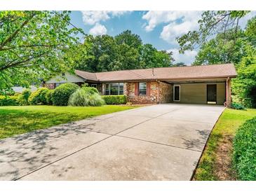 Charming one-story brick home featuring a covered carport, well-maintained lawn, and mature landscaping at 3854 Ridgewood Se Dr, Smyrna, GA 30080