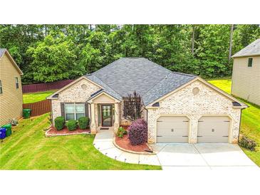 Charming brick home with a well-manicured lawn and a two-car garage at 4220 Sawgrass Dr, Lithonia, GA 30038