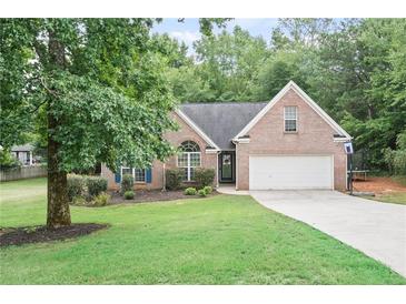 Charming brick home featuring a well-manicured lawn, mature trees, and a two-car garage at 7720 Paddocks Mill Dr, Cumming, GA 30041